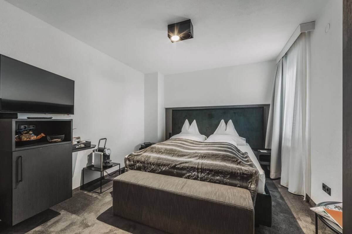 A hotel room with a bed, a TV, a desk, and a small table.