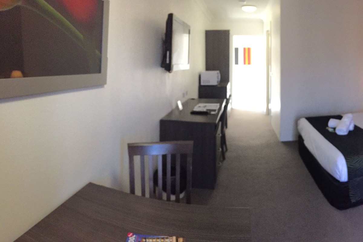 Ein Hotelzimmer mit Bett, Schreibtisch, Stuhl und Fernseher.