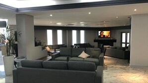 A modern living room with a sectional sofa, a fireplace, and large windows. - Hunts Hotel Liverpool (Casula)