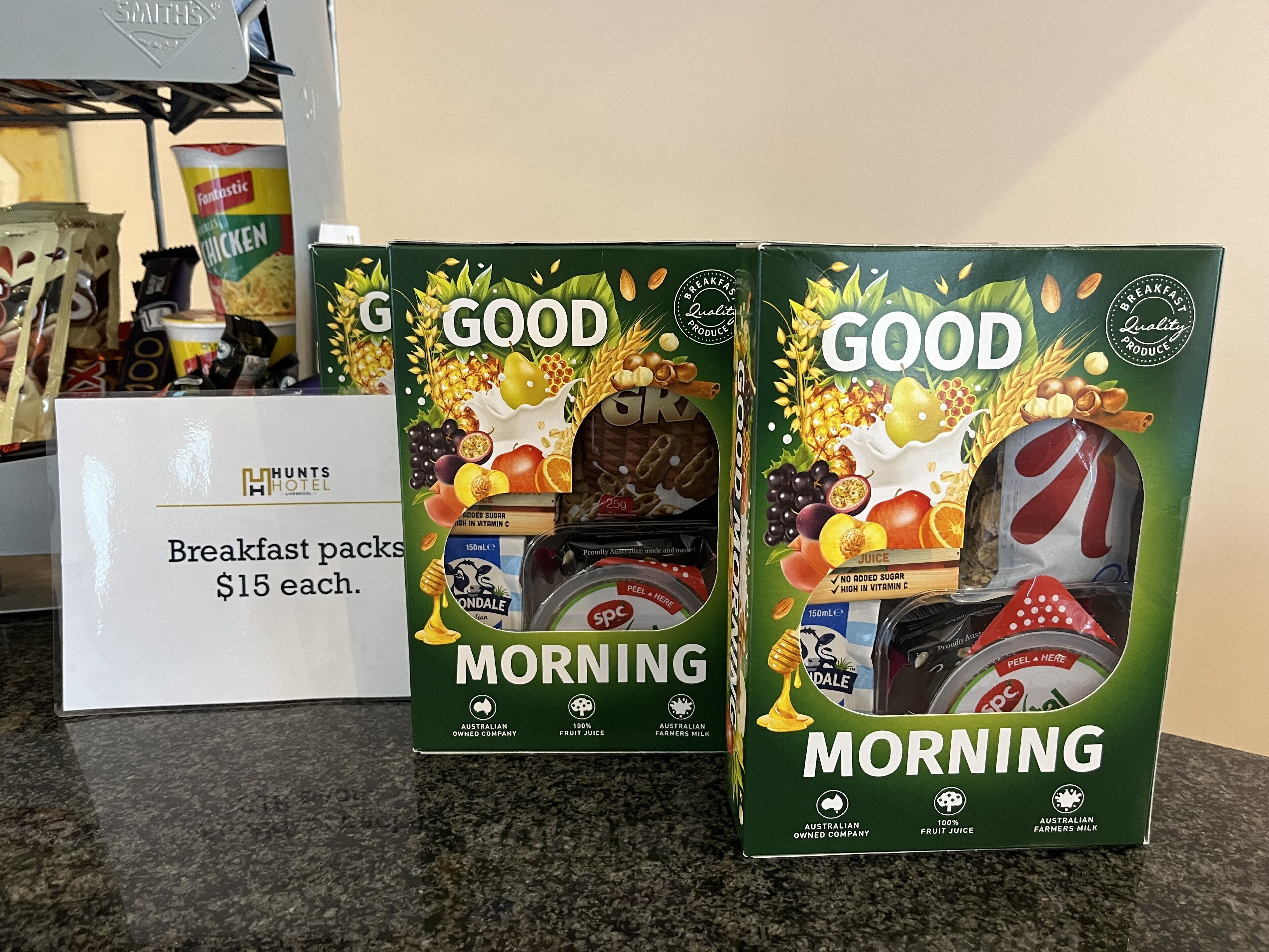 Two boxes of 'GOOD MORNING' breakfast packs priced at $15 each, with a sign indicating the price.