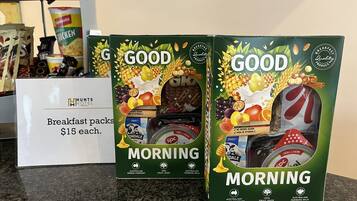 Two boxes of 'GOOD MORNING' breakfast packs priced at $15 each, with a sign indicating the price.