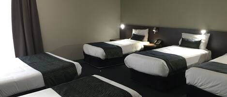 Una habitación de hotel con cuatro camas individuales, aire acondicionado en la pared y un teléfono junto a la cama.