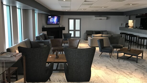 A modern hotel lobby with a seating area, a fireplace, a television, and a bar. - Hunts Hotel Liverpool (Casula)