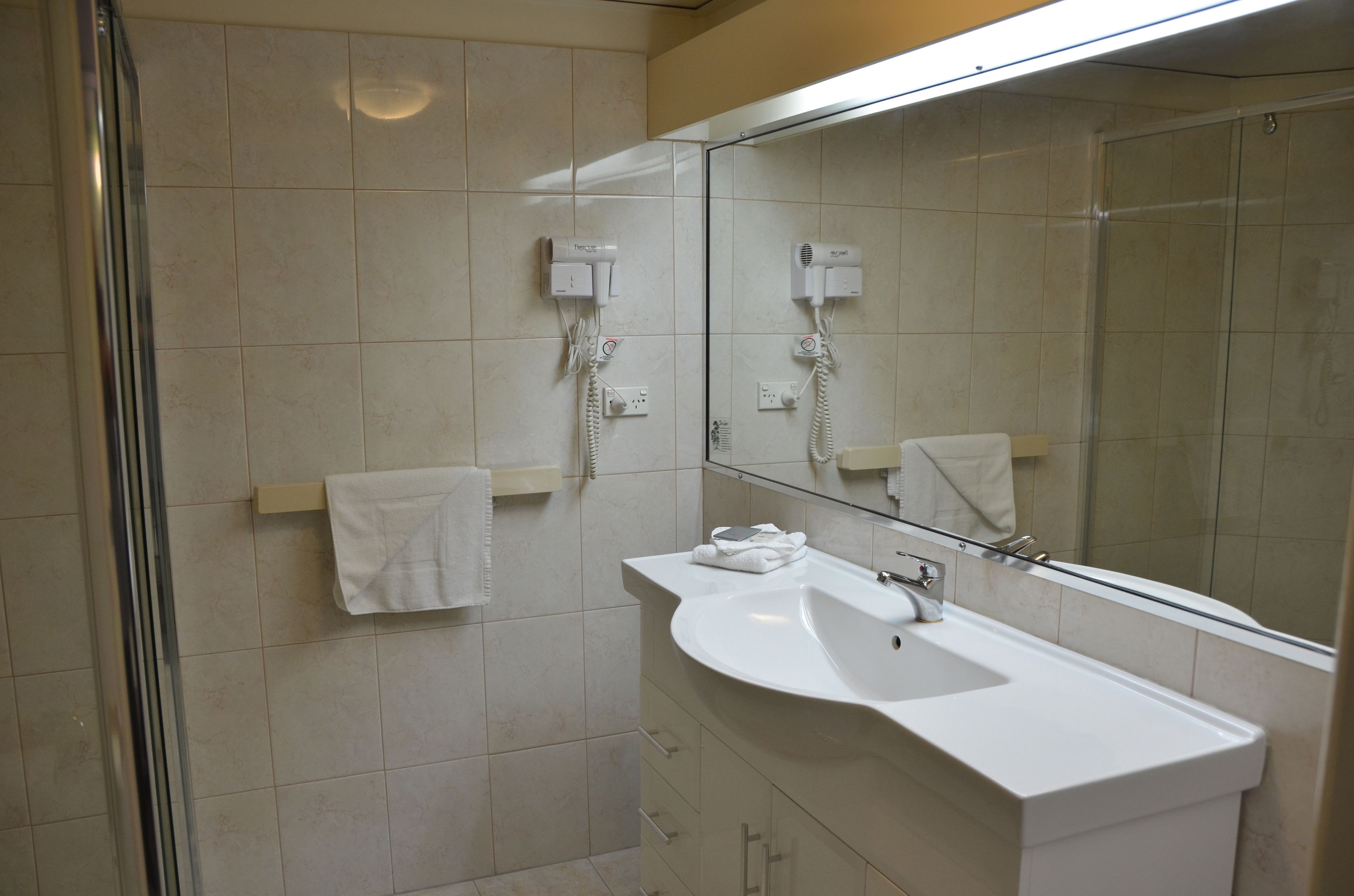 Un bagno moderno con uno specchio grande, un lavandino e una zona doccia.