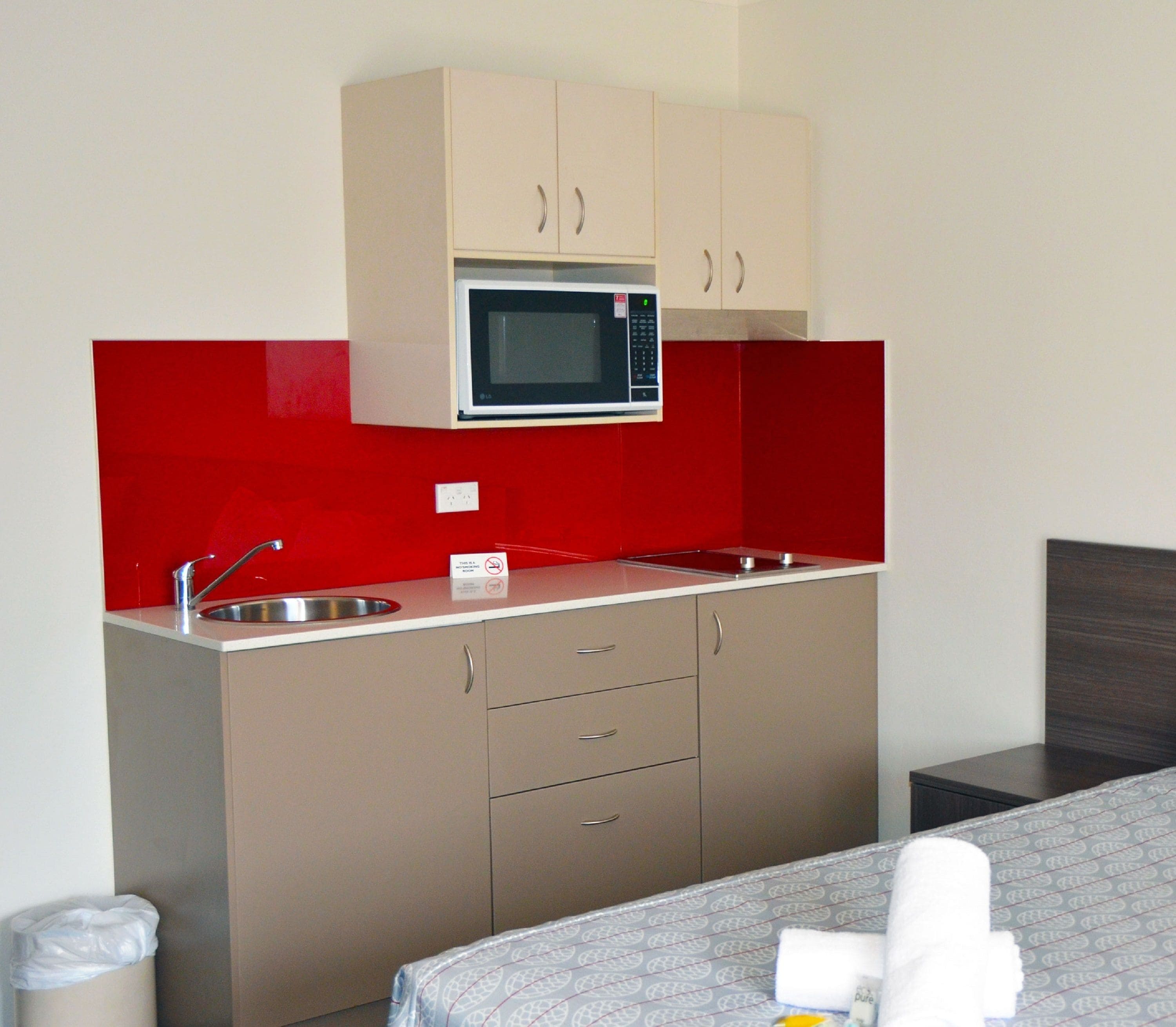 Una cocina compacta con microondas, pileta y placares.