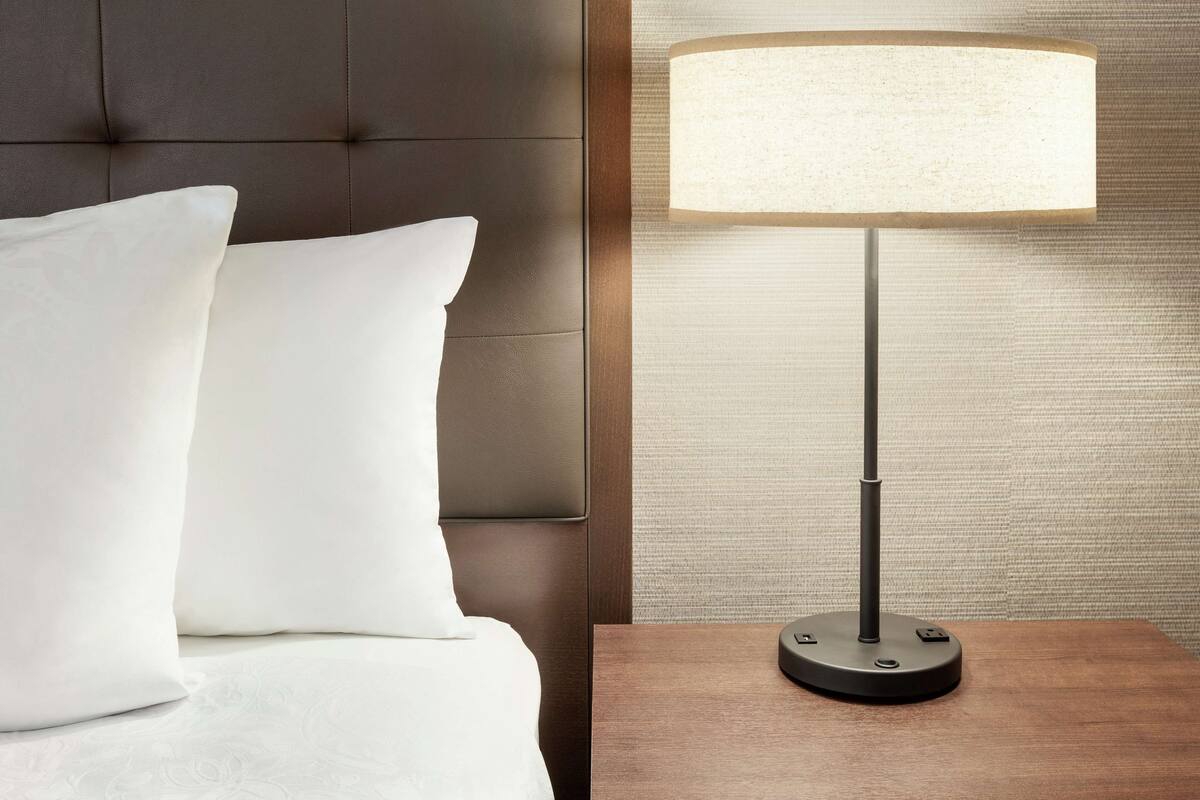 Ein Bett mit weißen Kissen und einem Nachttisch mit einer Lampe.