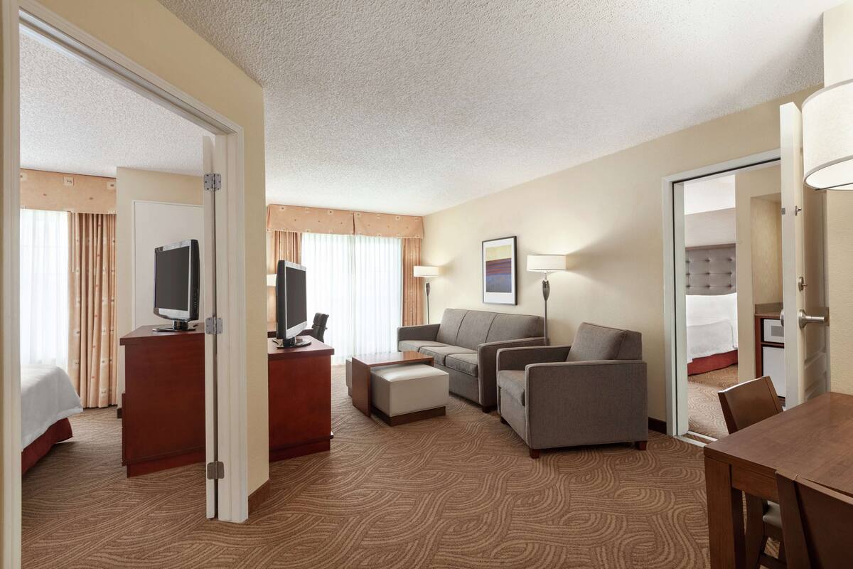 Ein Hotelzimmer mit Bett, Schreibtisch, Fernseher, Sofa, Couchtisch und Esstisch.