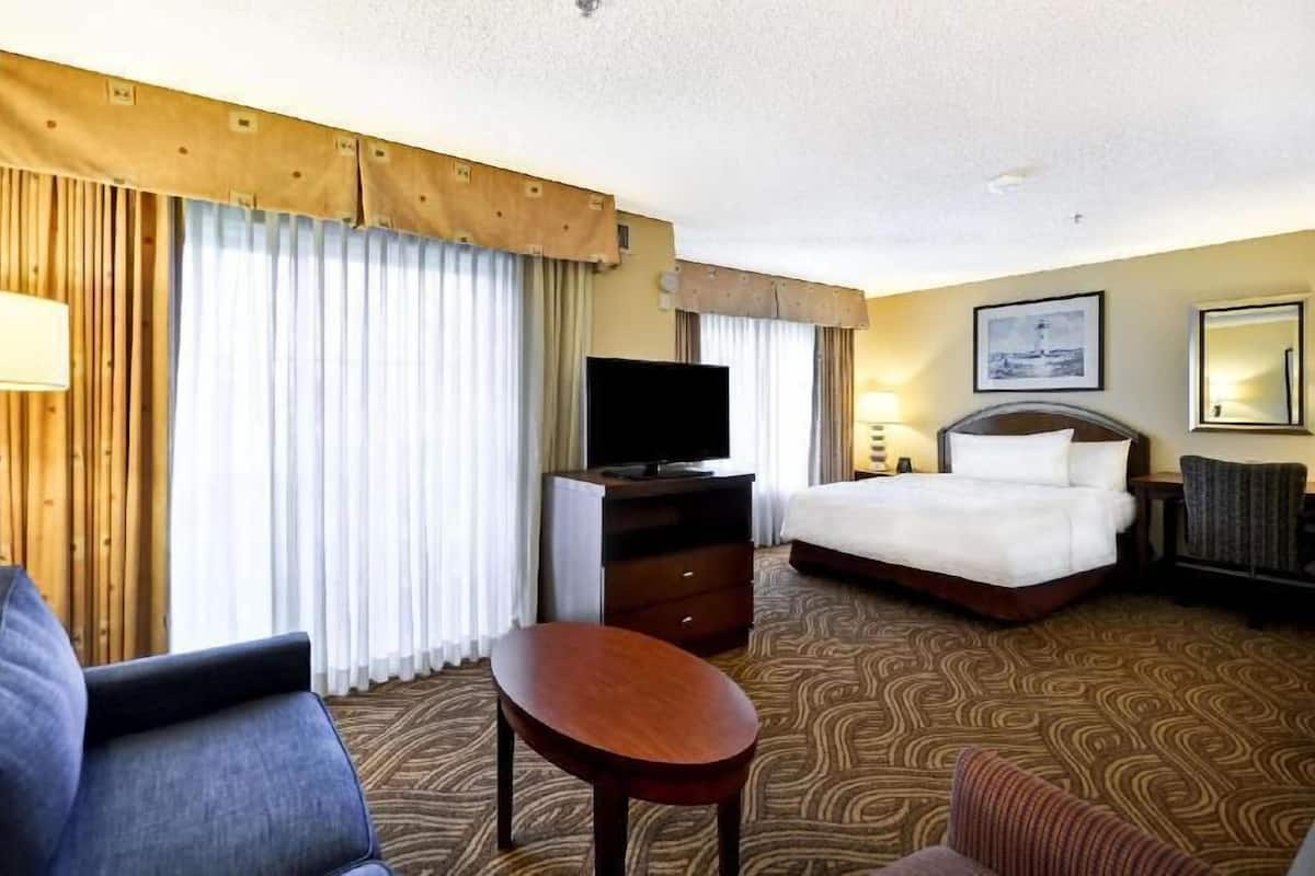 Ein Hotelzimmer mit Bett, Fernseher, Schreibtisch, Stuhl und einem gemusterten Teppich.