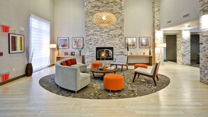 A spacious lobby with a fireplace, seating area, and a stone accent wall. - Homewood Suites by Hilton Oakland-Waterfront (Oakland)