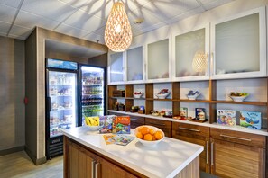 Une cuisine moderne dotée d’un îlot central, d’appareils électroménagers intégrés et de meubles de rangement en bois.