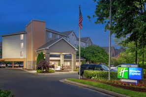 A hotel entrance with a flag, a sign for Holiday Inn Express, and a parking lot. - Holiday Inn Express Chapel Hill by IHG (Chapel Hill)