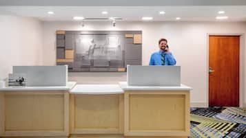 Een receptiebalie met een Holiday Inn Express bord, een houten vloer en een tapijt met een patroon.