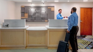 A reception desk area with a Holiday Inn Express sign, two receptionists, and a guest with a suitcase.