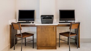 A workspace with two desks, each with a computer monitor, keyboard, and a printer.