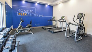 A gym with treadmills, dumbbells, and a motivational wall.