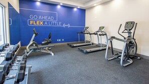 A gym with treadmills, dumbbells, and a motivational wall.