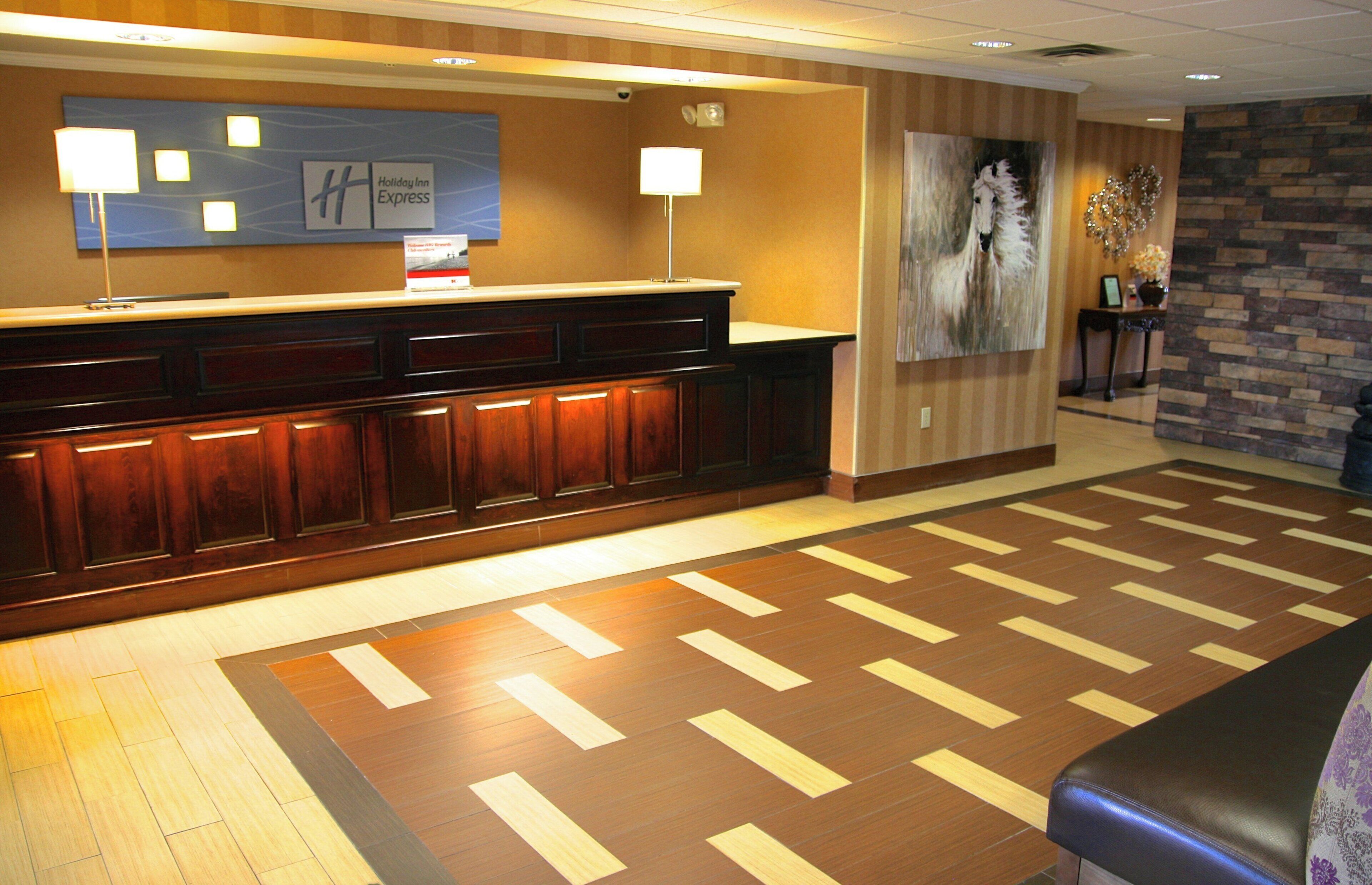 Un área de recepción con un mostrador de madera, un letrero de Holiday Inn Express y un cuadro grande en la pared.