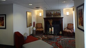 A room with a fireplace, two armchairs, a table with candles, and a large mirror.