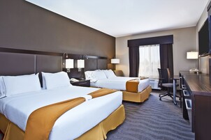 A hotel room with two beds, a desk, a chair, and a television.