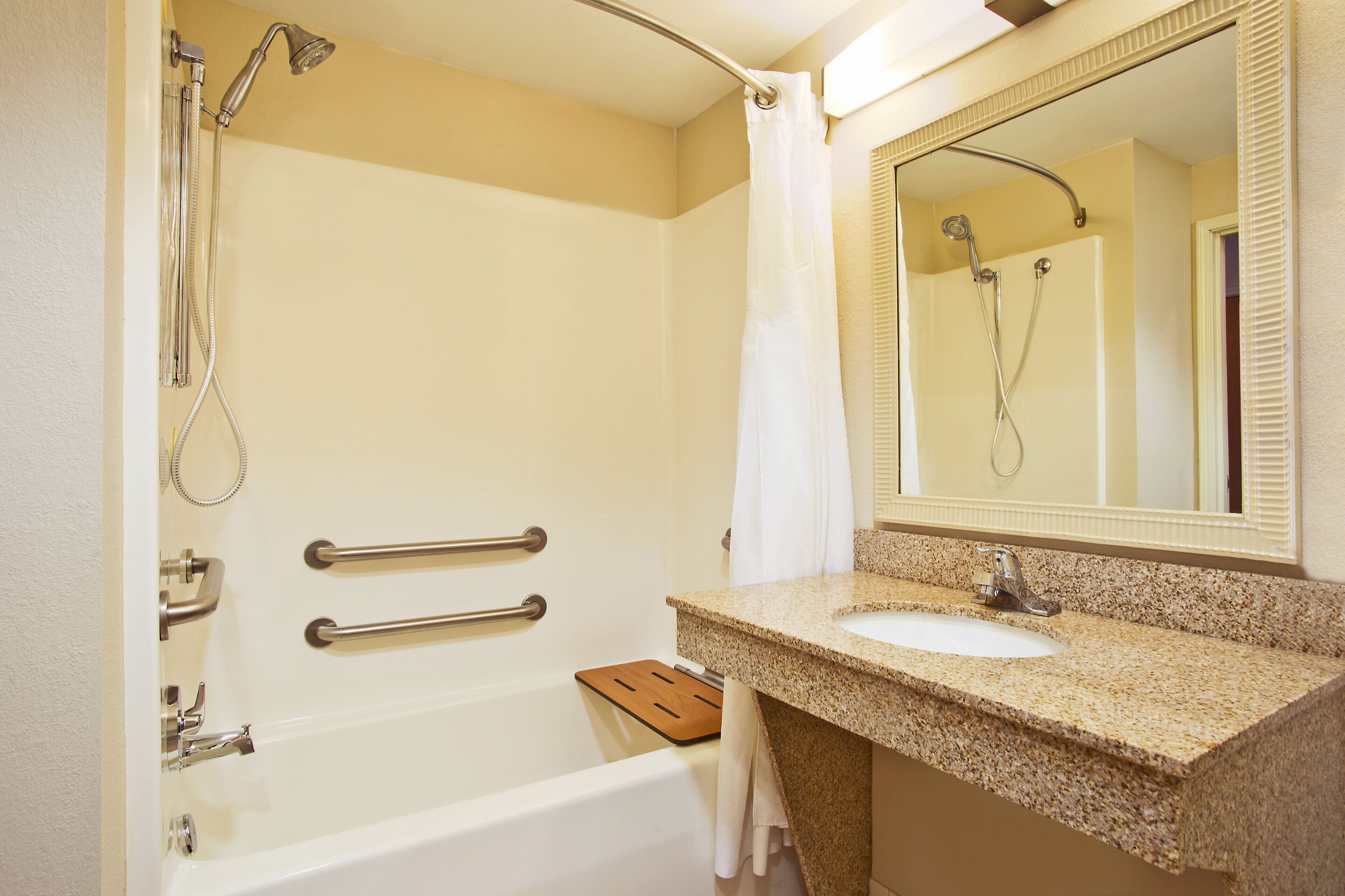 A bathroom with a bathtub, a sink, a mirror, and a shower.