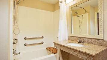 A bathroom with a bathtub, a sink, a mirror, and a shower.