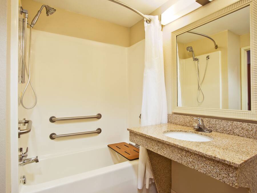 A bathroom with a bathtub, a sink, a mirror, and a shower.