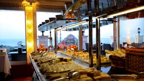 A buffet with various food items and a view of a mosque with a dome and minarets. - Deluxe Golden Horn Sultanahmet Hotel (Istanbul)