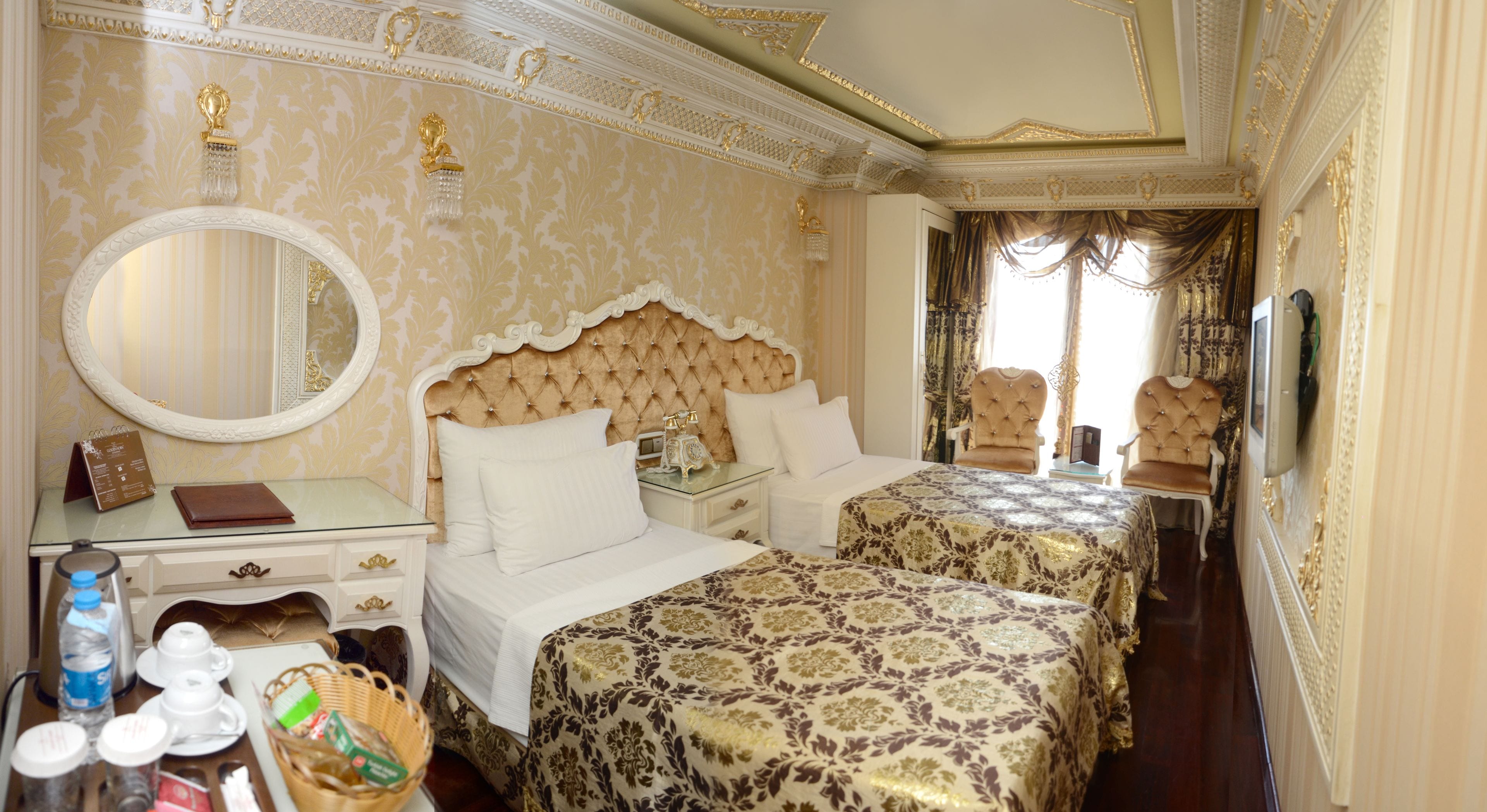 Una lujosa habitación de hotel con una cama grande, un área de estar separada, un tocador con espejo y un televisor.