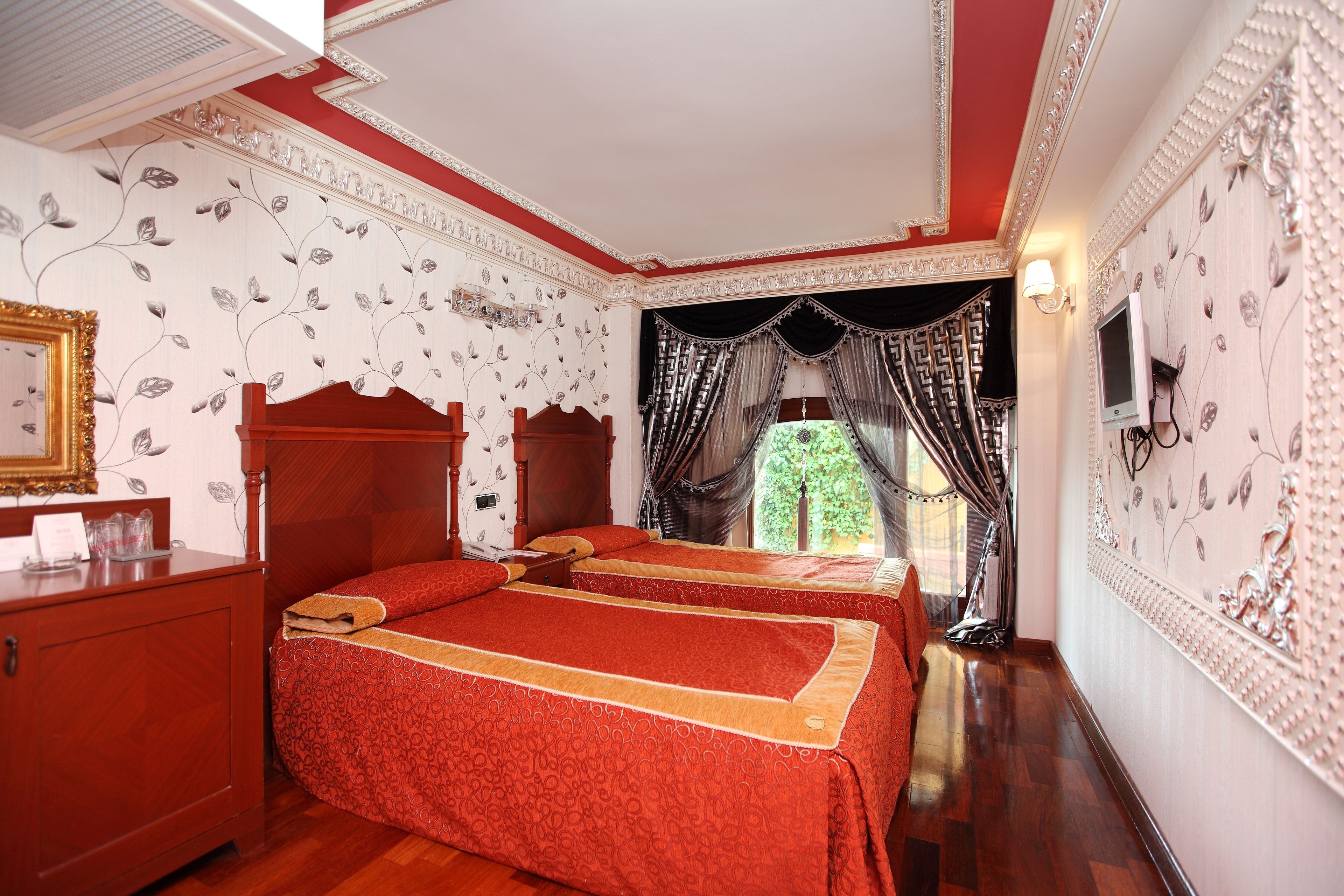 A hotel room with two beds, a wooden dresser, and a television.