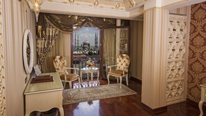 A luxurious room with ornate decor, a view of a mosque, and a seating area with a glass table. - Deluxe Golden Horn Sultanahmet Hotel (Istanbul)
