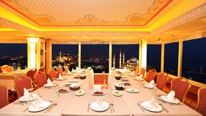 A luxurious dining room with ornate ceiling and large windows offering a city view at night. - Deluxe Golden Horn Sultanahmet Hotel (Istanbul)