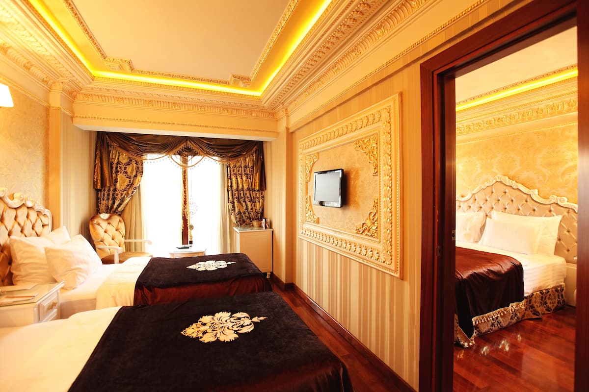 Une chambre d’hôtel luxueuse, dotée de deux lits, d’une télévision et de décorations murales raffinées.