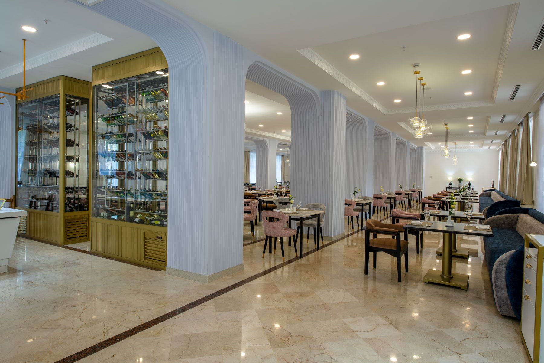 Un restaurante espacioso con techos altos, pisos de mármol y diferentes opciones de asientos, incluyendo mesas y sillas.