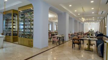A spacious restaurant with high ceilings, marble floors, and a variety of seating arrangements including tables and chairs.