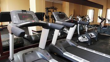 Un gimnasio con cintas de correr, una bicicleta estática y una máquina de remo.