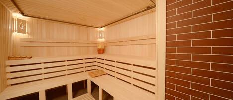 A sauna with wooden benches and a brick wall.