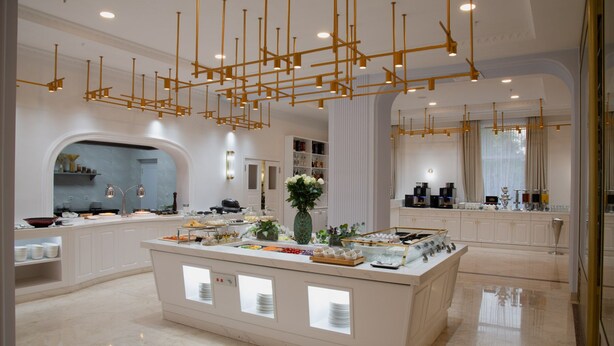 Una cocina moderna con una isla central, armarios blancos e iluminación colgante dorada.