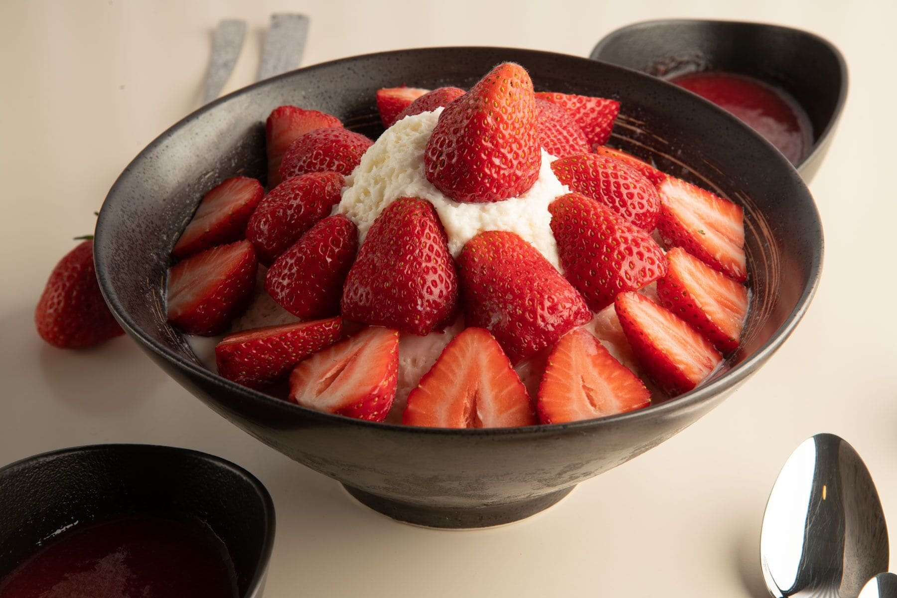A bowl of strawberries and whipped cream on a table.