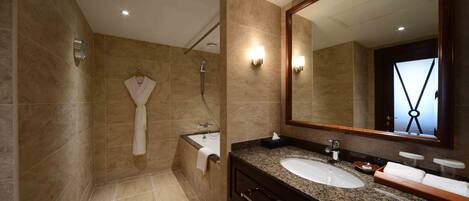 A modern bathroom with a large mirror, a sink, and a bathtub.