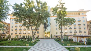 Un patio de hotel con un camino empedrado, árboles y un edificio con varios balcones.