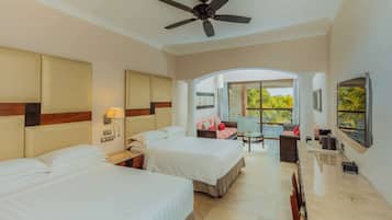 Habitación de hotel con dos camas, un ventilador de techo, televisión y vistas al exterior.