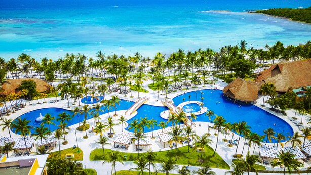 Un resort con múltiples piscinas, palmeras y vistas a la playa.