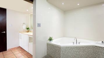 Un baño moderno con una bañera grande, azulejos blancos y una pequeña planta en maceta.