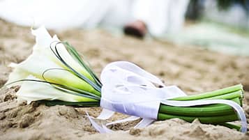 A bouquet of flowers on a sandy surface with a couple in the background.