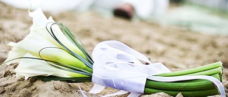 A bouquet of flowers on a sandy surface with a couple in the background.