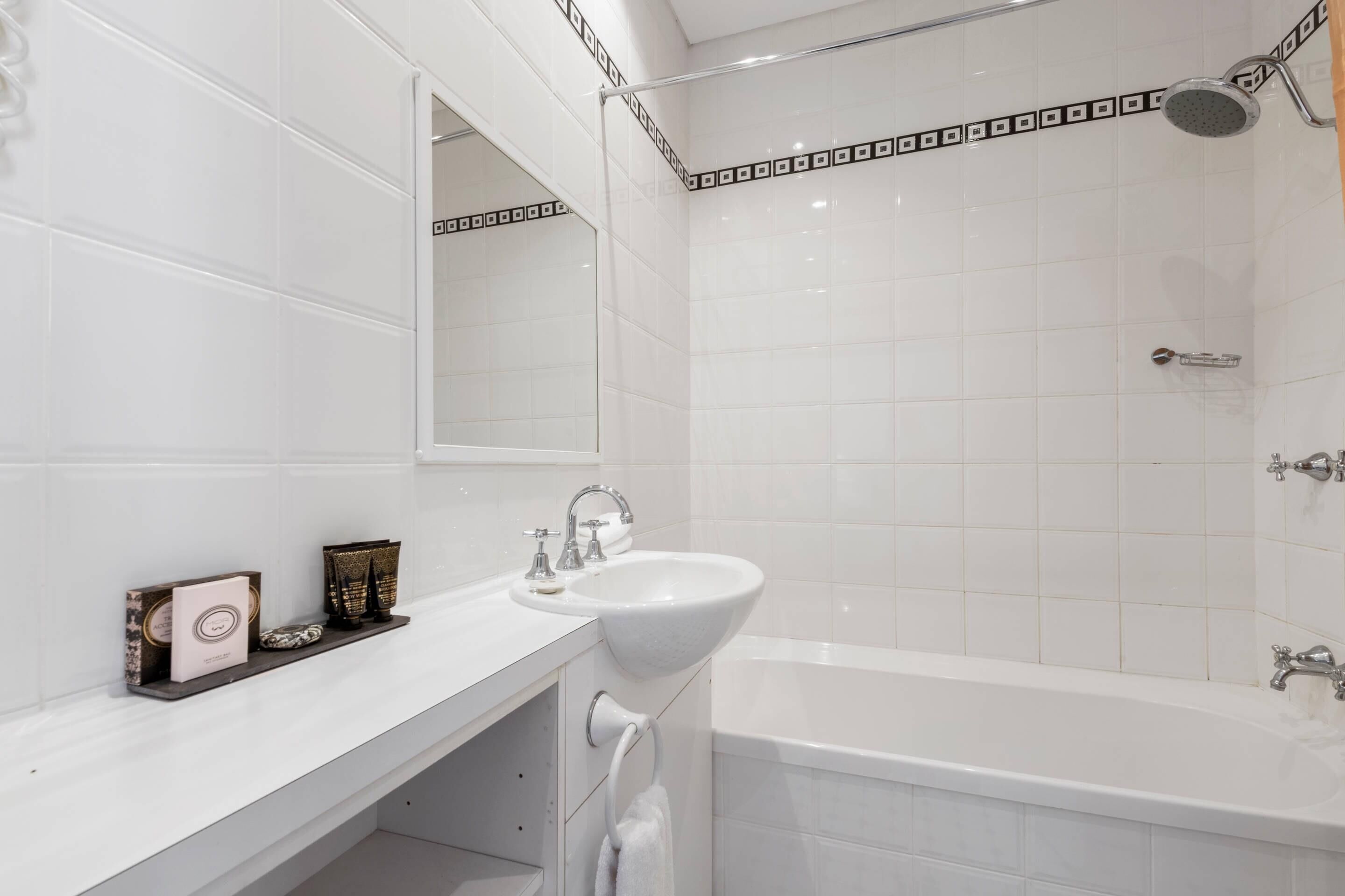 A modern bathroom with a white sink, a bathtub, and a shower.
