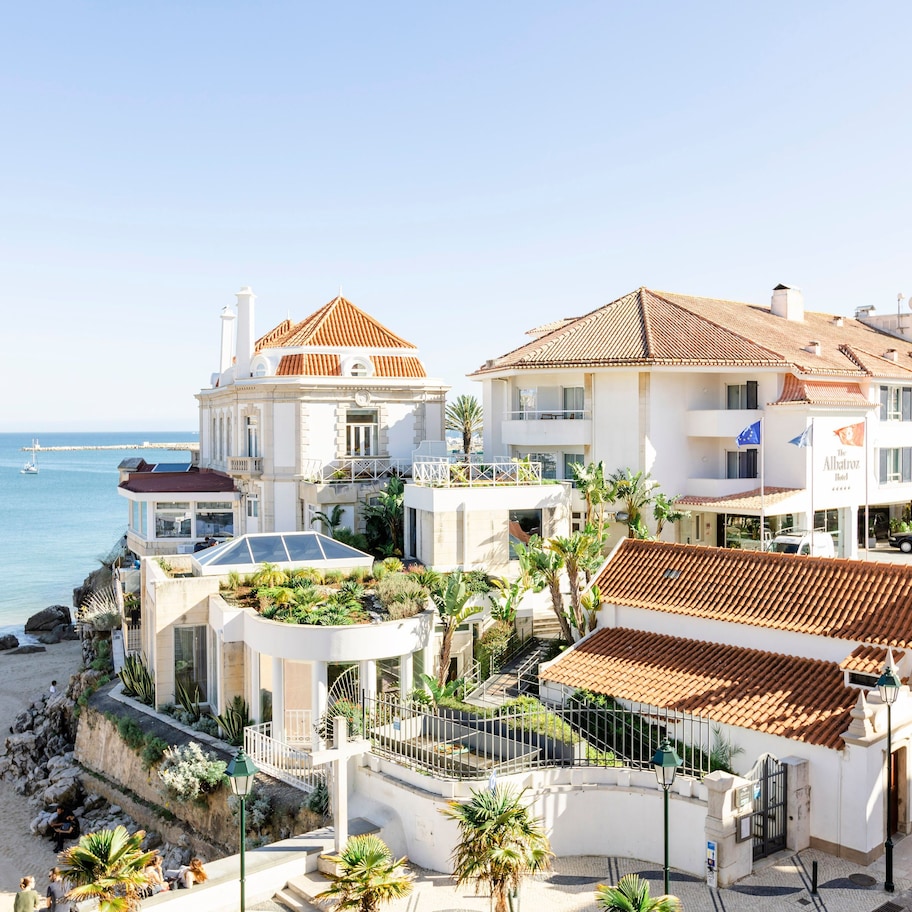 A coastal hotel with multiple buildings, a beach, and a clear view of the sea.