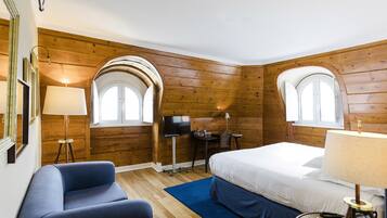 Habitación de hotel con paredes de madera, una cama, un escritorio, una silla y un televisor.