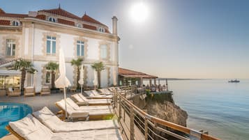 Una piscina al aire libre, sombrillas, sillones reclinables de piscina