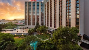 Un hotel Marriott con diseño moderno, que cuenta con una piscina en la azotea y exuberante jardinería.